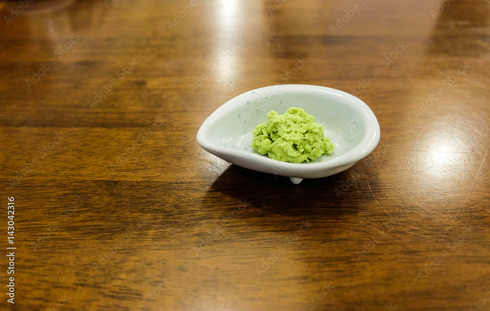Wasabi Japanese herb in white small bowl on the wood table, close up Wasabi Japanese herb in white small bowl on the wood table, close up