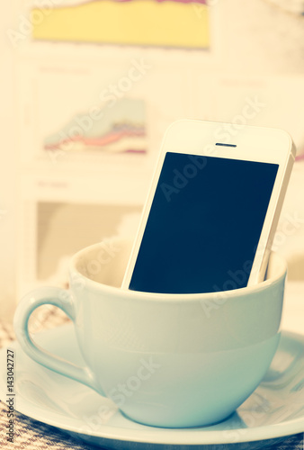 Smart phone  and  coffee cup with business graph chart background,retro filter image