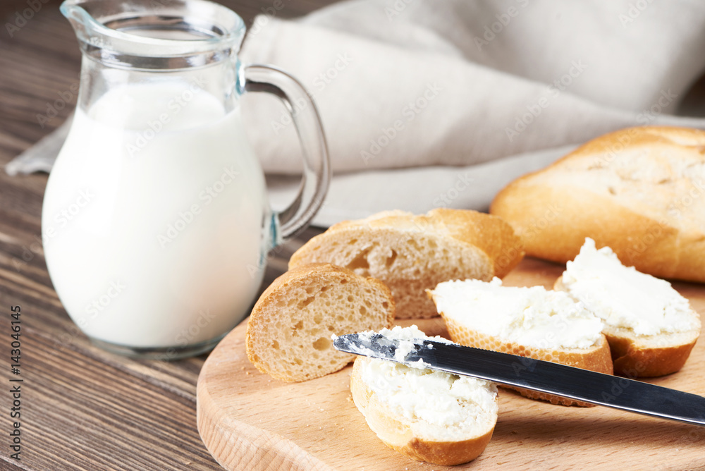 Sliced bread with creamy curd on wooden plank Sliced bread with creamy curd on wooden plank