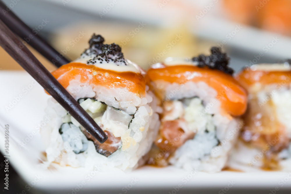 Sushi roll and black chopsticks Sushi roll and black chopsticks