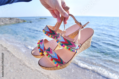 bohemian greek sandals on the beach - summer shoes advertisement