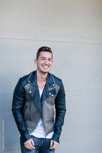 Junger Mann mit Lederjacke vor Garagenwand © Nena