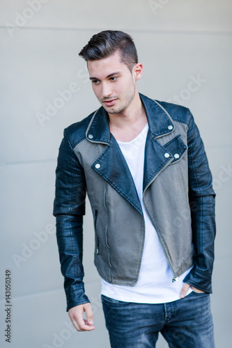 Junger Mann mit Lederjacke vor Garagenwand
