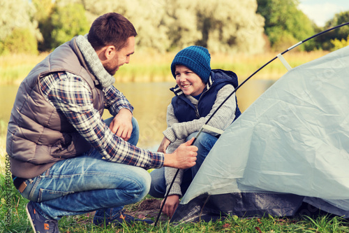 happy father and son setting up tent outdoors