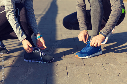 close up of couple tying shoelaces outdoors