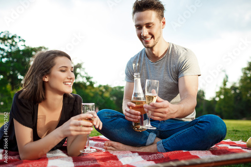 Young beautiful couple smiling, resting on picnic in park.
