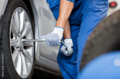 mechanic with screwdriver changing car tire © Syda Productions