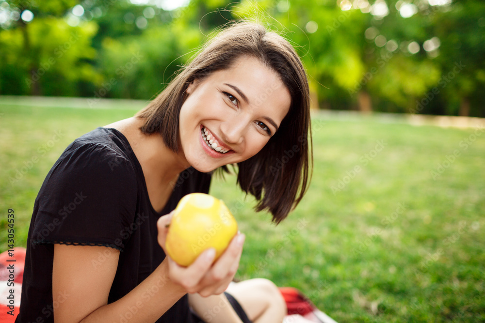 Young beautiful girl smiling, holding apple on picnic in park. Young beautiful girl smiling, holding apple on picnic in park.
