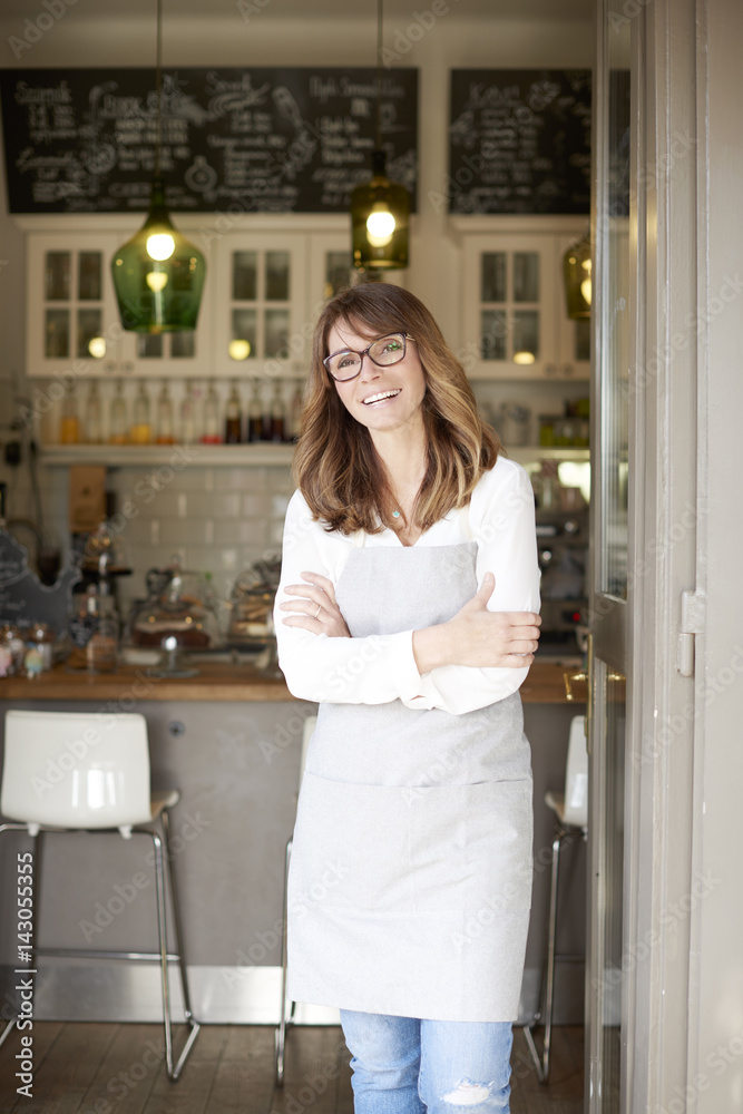 Proud small coffee shop owner businesswoman. Shot of a happy barista woman standing at doorway and inviting to her coffee shop. Small business. Proud small coffee shop owner businesswoman. Shot of a happy barista woman standing at doorway and inviting to her coffee shop. Small business.