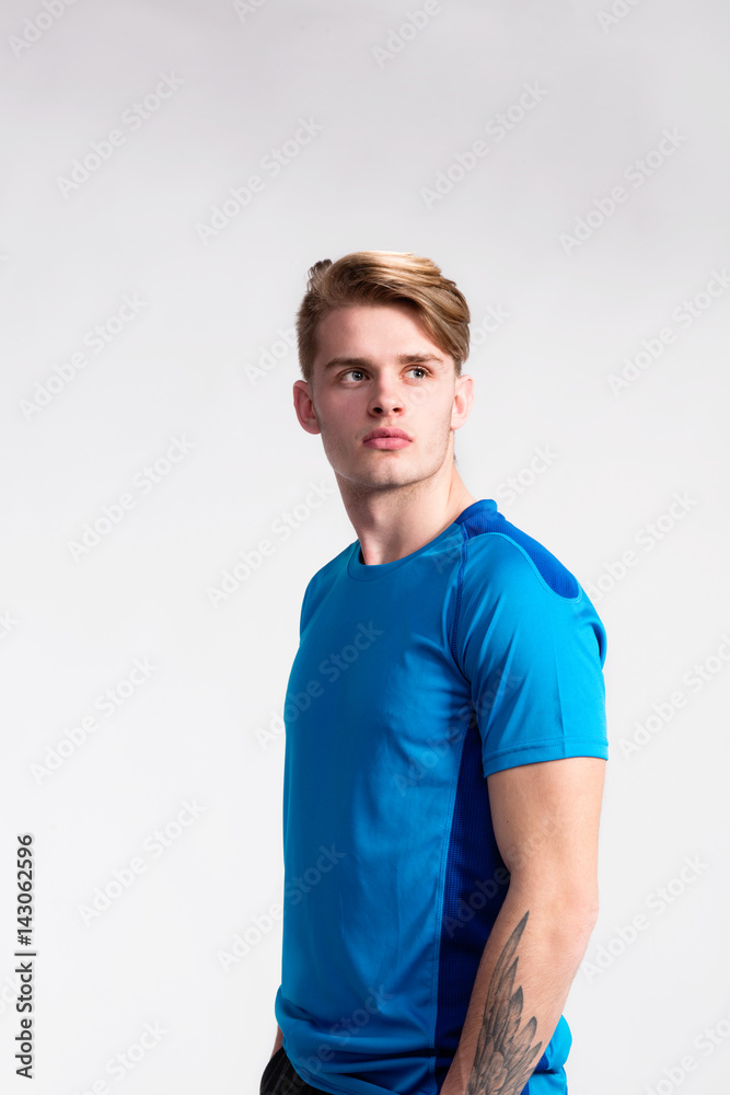 Obraz premium Young handsome hipster man in blue sports t-shirt, studio shot.
