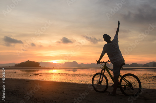 Silhouette of a man riding bicycle on beach © tippapatt