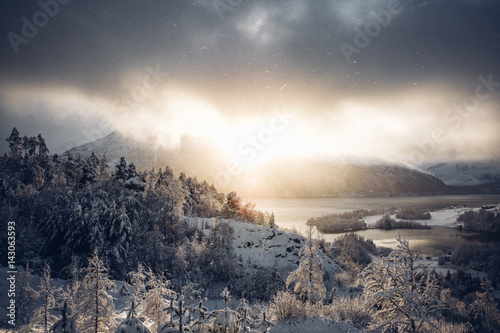 Snowscape, sunshine, mountains, lake and stormy sky  photo