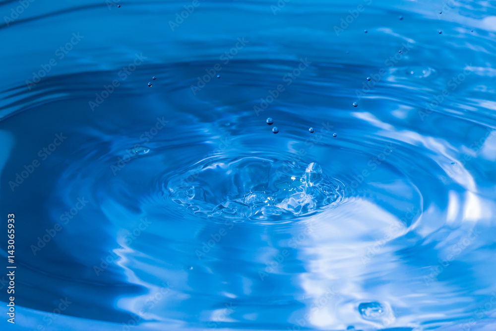 Water splash in dark blue color with a drop of water flying from above Water splash in dark blue color with a drop of water flying from above
