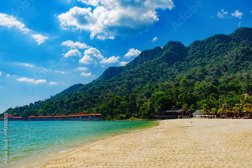 Relaxing on remote paradise beach. Tropical bungalow and luxury house on untouched sandy beach with palms trees in Langkawi Island, Malaysia.