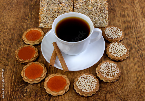 A cup of coffee and biscuits on a wooden table. © sosiukin