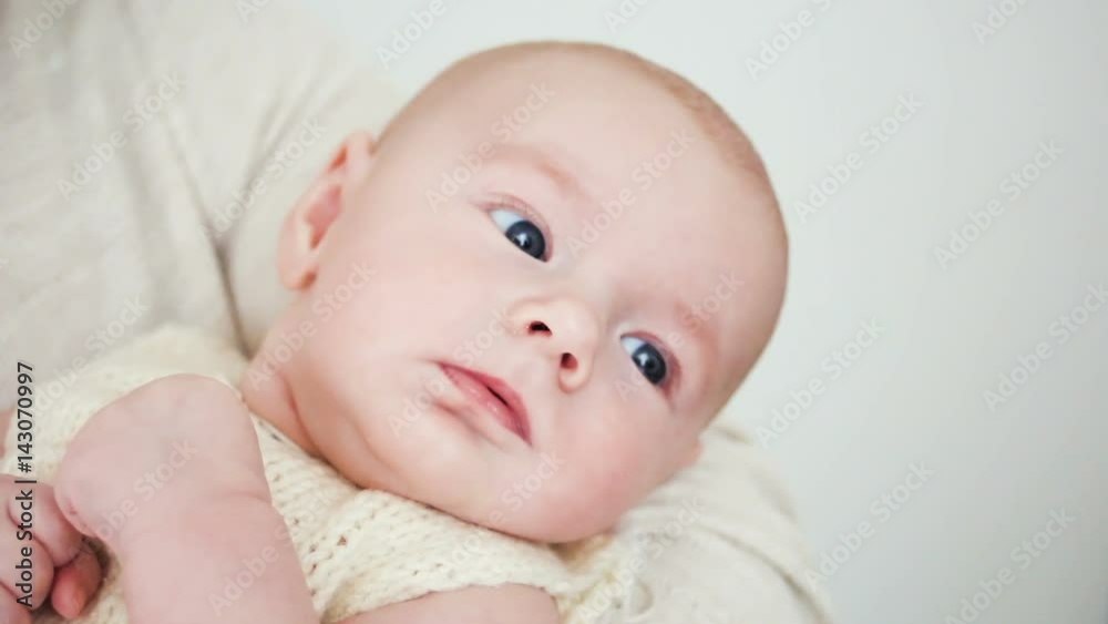 baby is lying on the hands of her mother and looks baby is lying on the hands of her mother and looks