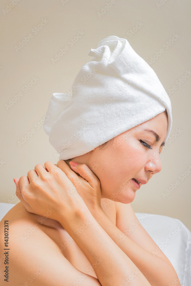 Young woman sitting on the bed suffering from pain in neck Young woman sitting on the bed suffering from pain in neck