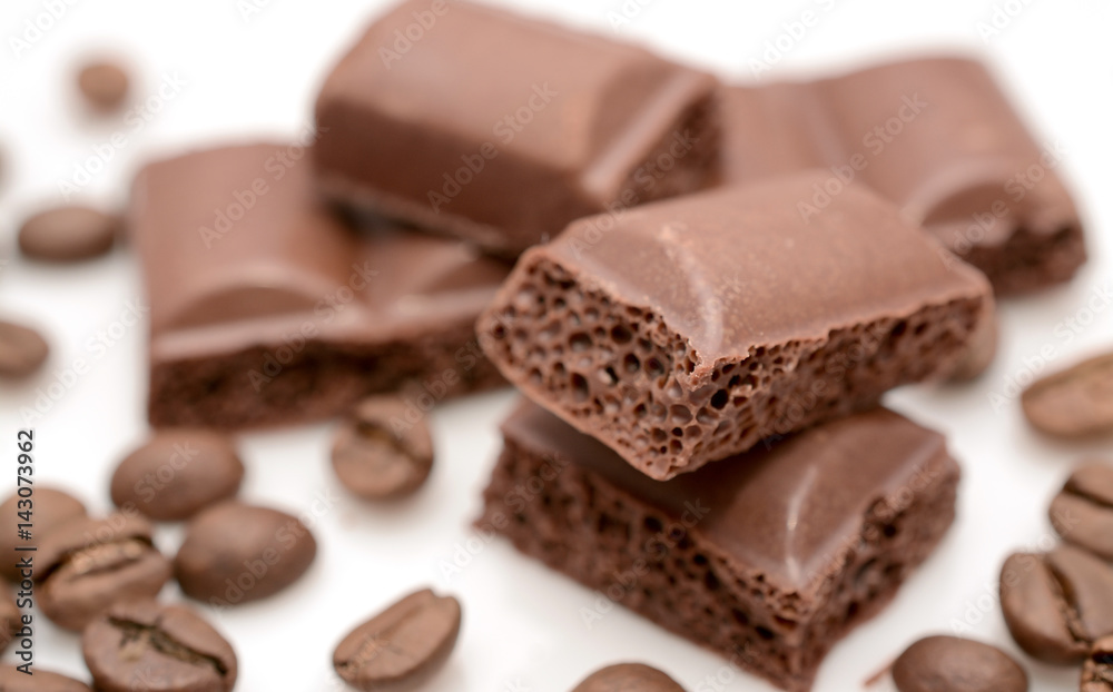 Chocolate slices close-up and coffee beans on a white background. Chocolate slices close-up and coffee beans on a white background.