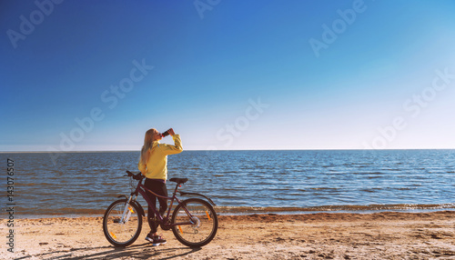 A girl on a bicycle by the sea