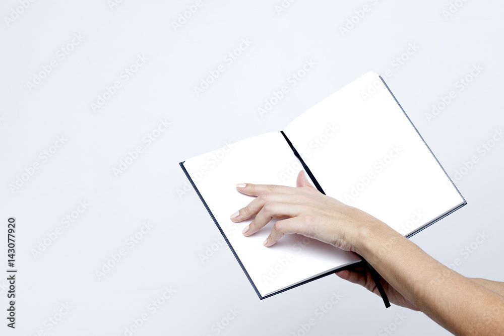Opened notebook with white pages close-up in the women's hands on a white background Opened notebook with white pages close-up in the women's hands on a white background
