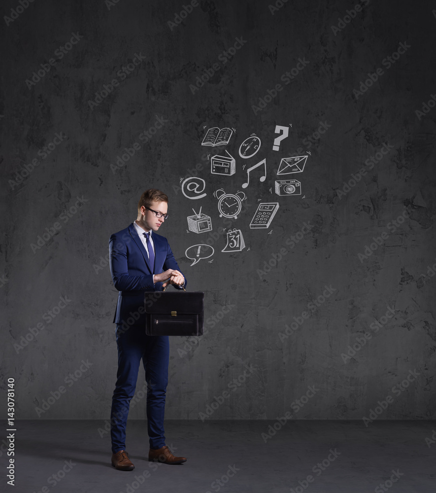 Businessman with briefcase checking time on a dark dramatic background. Business and office, concept. Businessman with briefcase checking time on a dark dramatic background. Business and office, concept.