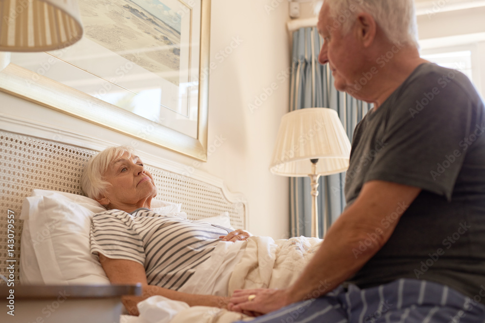 Senior man taking care of his sick wife in bed Senior man taking care of his sick wife in bed