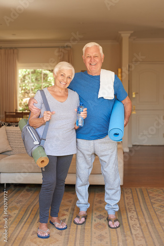 Active senior couple prepared for yoga standing together at home