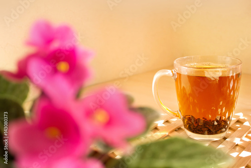 Cup glass of black tea on a wooden background. Morning, sunny and warm weather