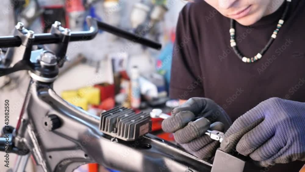 Young males mechanic assembling a custom cafe racer motorcycle in a garage Young males mechanic assembling a custom cafe racer motorcycle in a garage