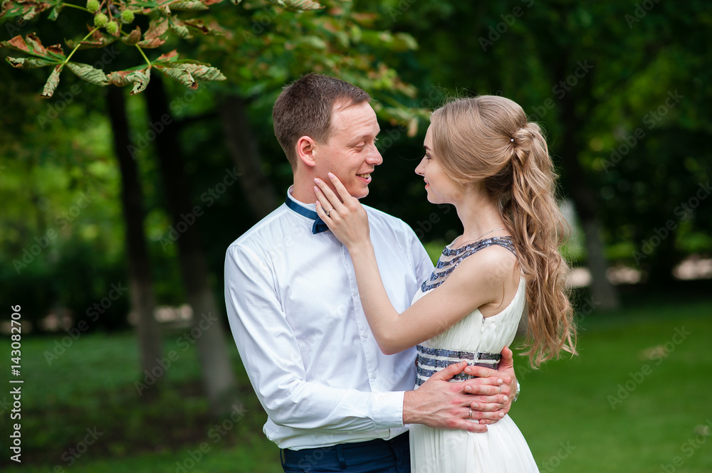 A married couple is walking and hugging in the park.