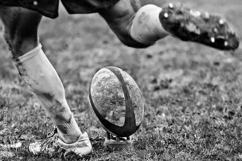 Fototapeta Legs of rugby player kicking ball