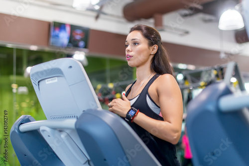 Fit woman exercising on treadmill in gym.