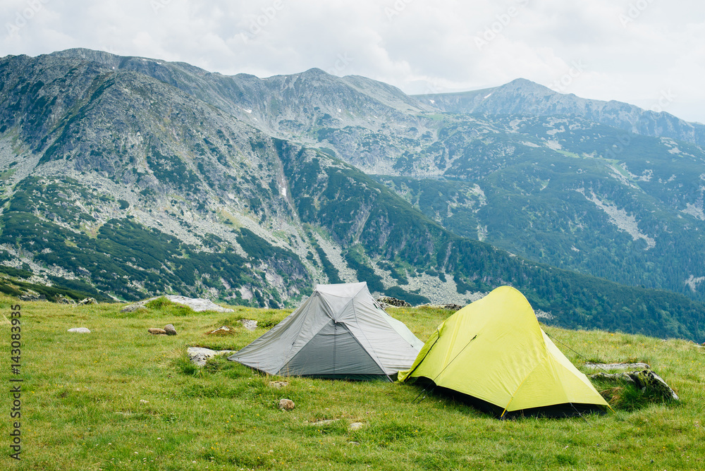 Two tents on the green background of the rocky Romanian mountains