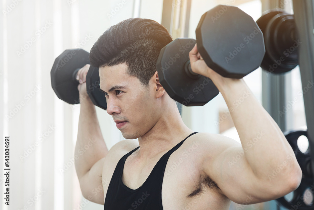 Asian Muscular man lifting dumbbells in gym. copy space. Asian Muscular man lifting dumbbells in gym. copy space.