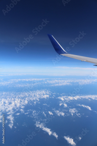 An airplane s wing over a blue and cloudy sky