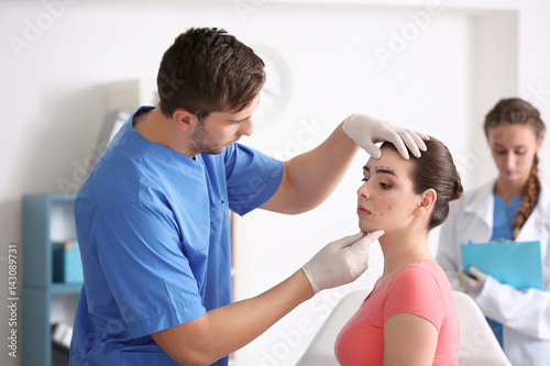 Fotografija Plastic surgeon examining young woman's face prior to operation in clinic