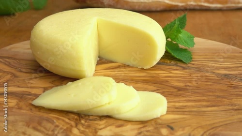 Camera movement near head Babybel semi-hard cheese on the rustic table with sliced pieces photo