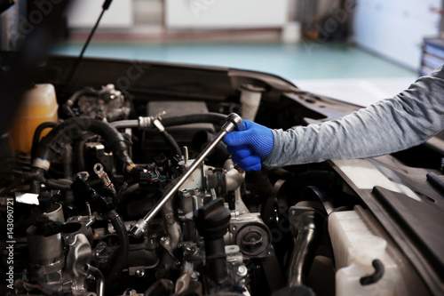 Mechanic hand repairing car with open hood, closeup