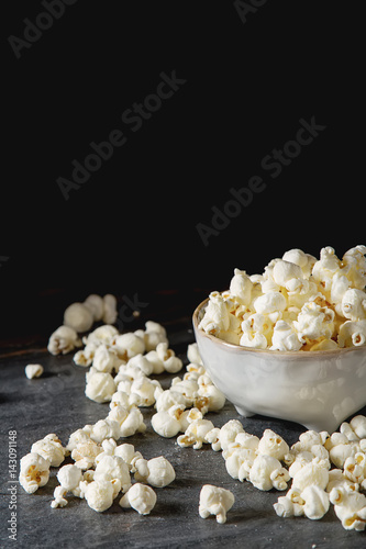 Salted popcorn in a cup. Dark background. Selective focus. Fast food for movies.