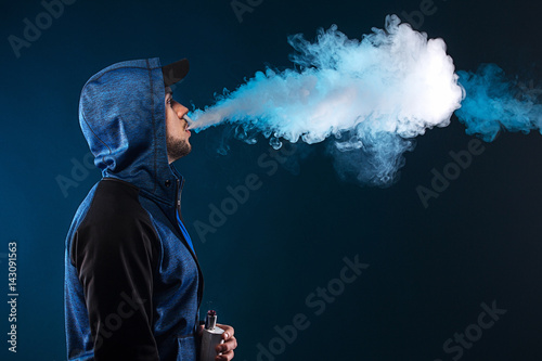vaping man holding a mod. A cloud of vapor. photo