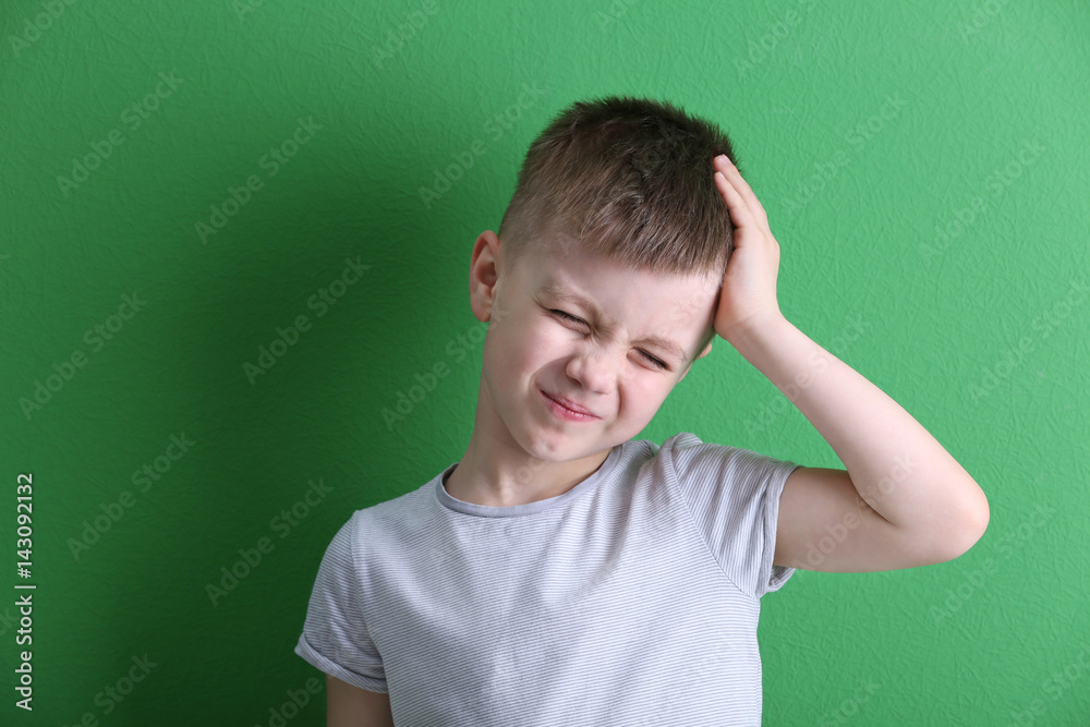 Little boy suffering from headache on color background Little boy suffering from headache on color background