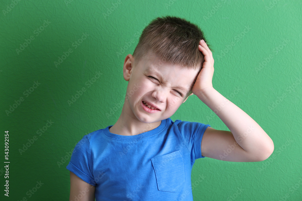 Little boy suffering from headache on color background Little boy suffering from headache on color background