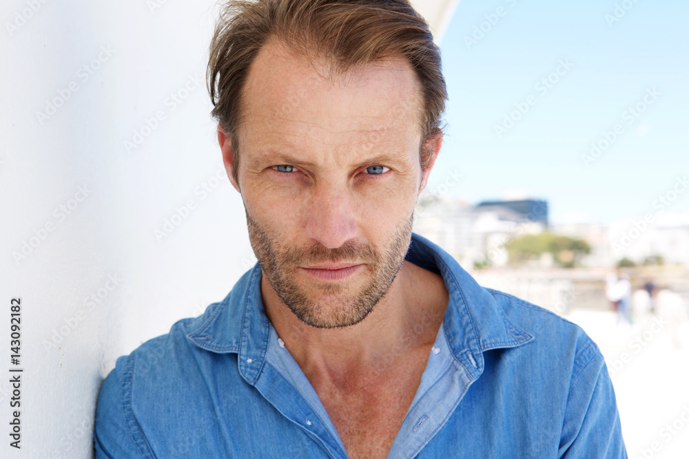 Fototapeta premium Close up cool older man leaning against wall and staring