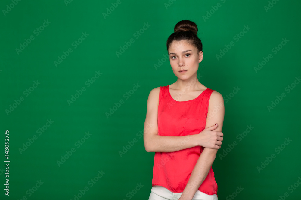 Beautiful young girl in a red blouse and white trousers on a green background