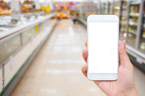 Woman hold mobile phone while shopping in supermarket
