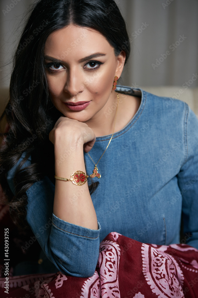 Portrait of Beautiful brunette, young oriental beauty female model with black long hair, Dressed in a denim dress clothing with Oriental red scarf and oriental jewelry.