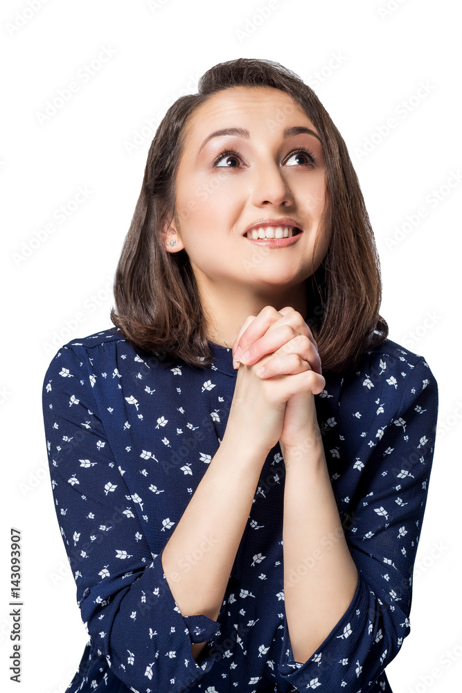 beautiful brunette girl with short hair in blue dress fingers crossed hands together, looking up with a pleading smile happiness emotions beautiful brunette girl with short hair in blue dress fingers crossed hands together, looking up with a pleading smile happiness emotions