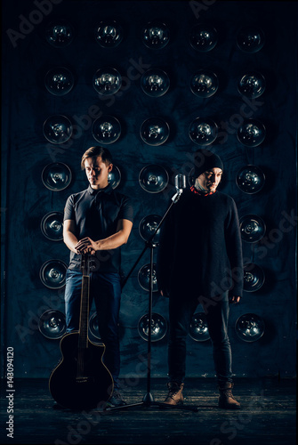 two rock musician with a guitar standing in the hall with the lights look in the dark