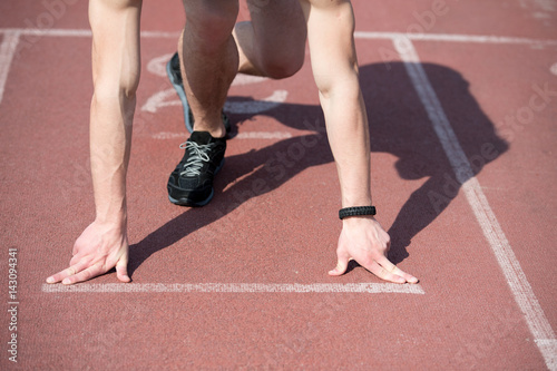 man runner with muscular hands, legs start on running track