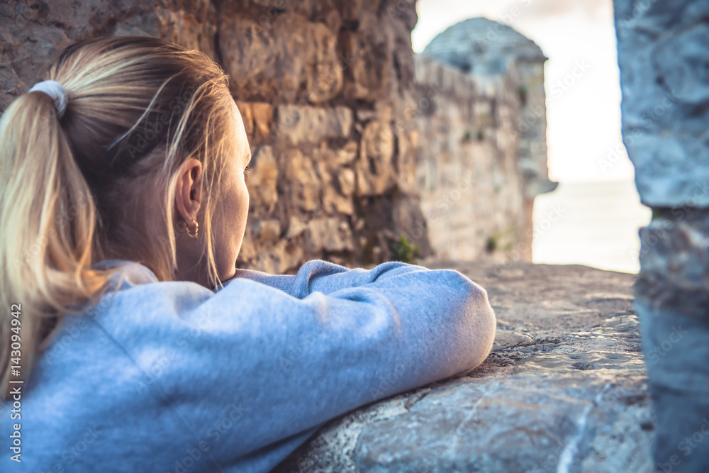 Pensive thoughtful woman looking at beautiful view through window during sunset. Sunlight illuminate woman face. Concept for forecasting and way forward